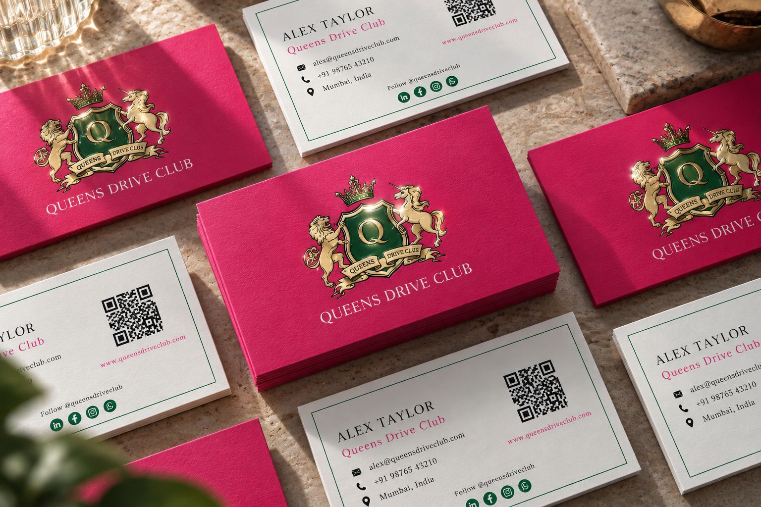 Queens Drive Club business cards in magenta and ivory, showing the gold and green heraldic crest with lions, unicorn and crown